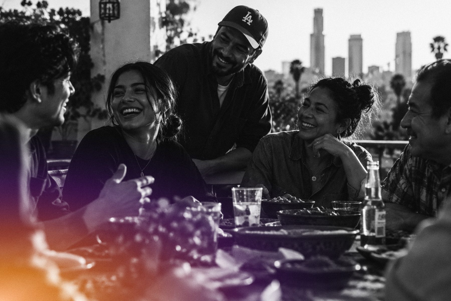A multigenerational family sharing a meal on a terrace overlooking the Los Angeles skyline